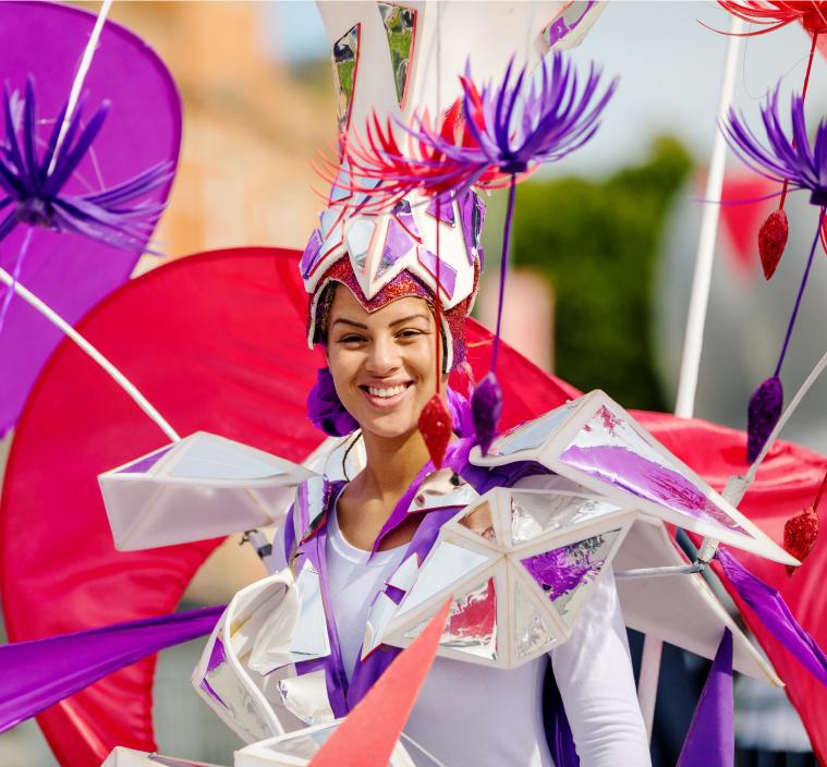 A lady dressed in bright festival clothing smiles at the camera